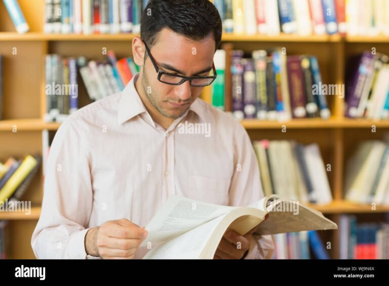 aikuinen opiskelija kirjastossa lukemassa kirjaa