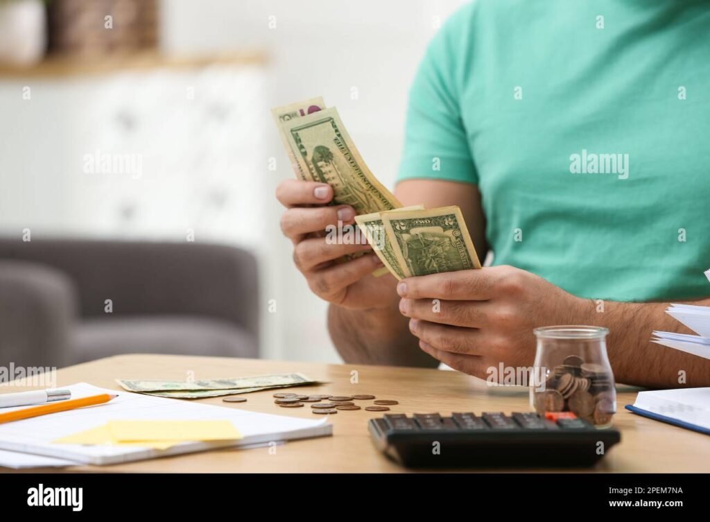 henkilo laskemassa rahaa poydan aaressa