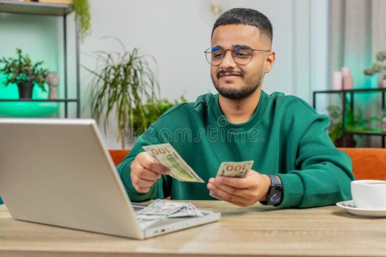 hymyileva henkilo tietokoneen aarella laskemassa palkkaa