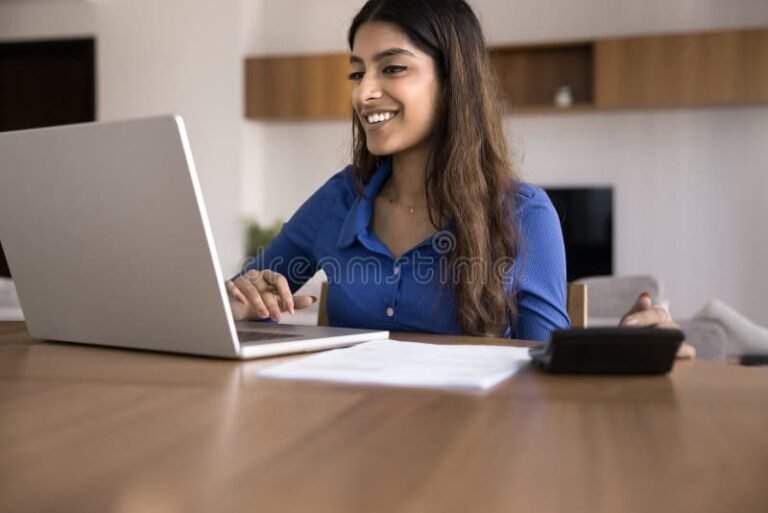 hymyileva tyontekija laskemassa laskuria tietokoneella