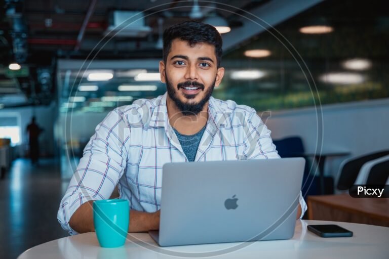 ihminen kayttaa kannettavaa tietokonetta iloisesti